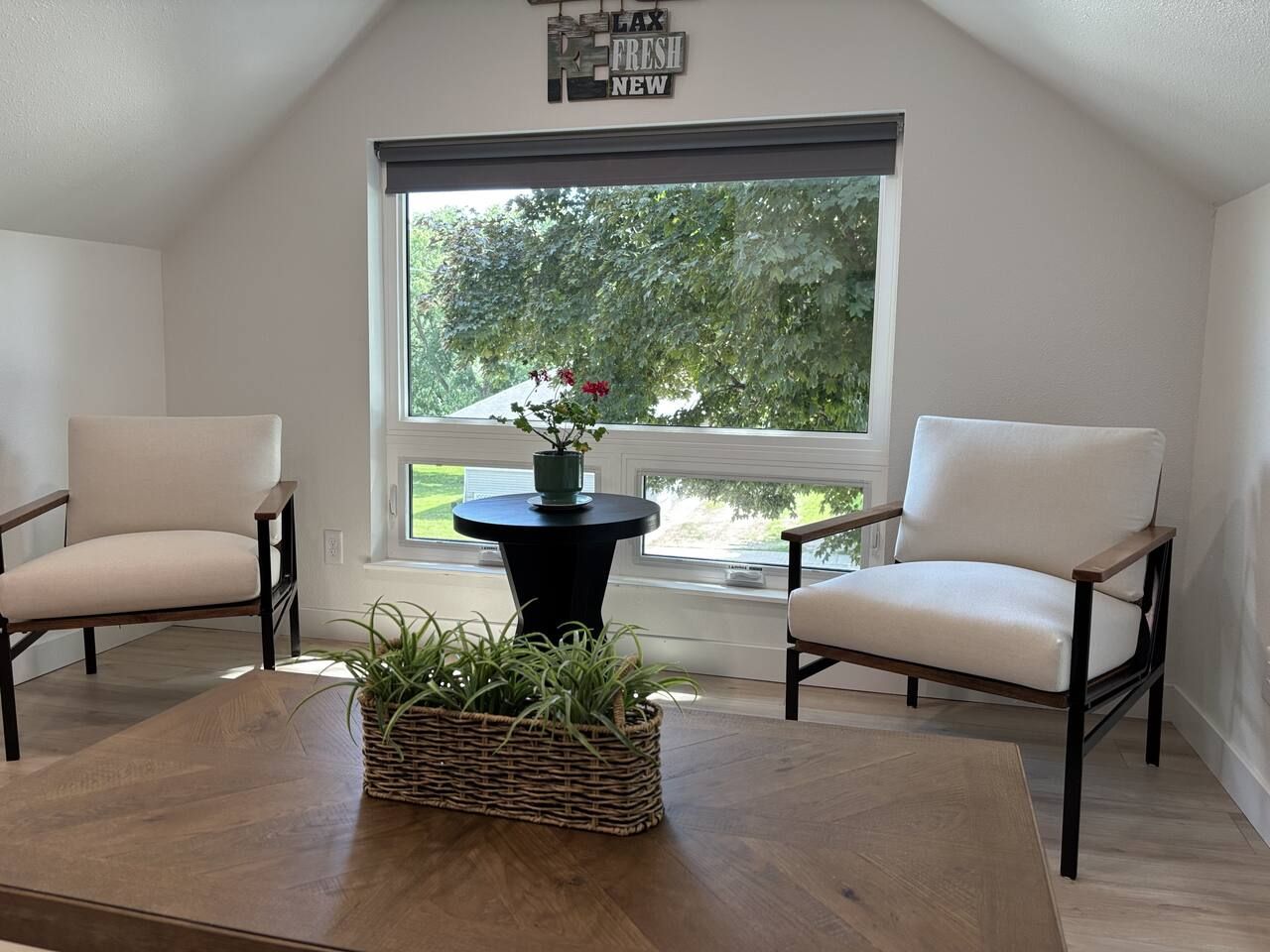 Una habitación con dos sillas, una mesa y un ventanal con vistas a zonas verdes.