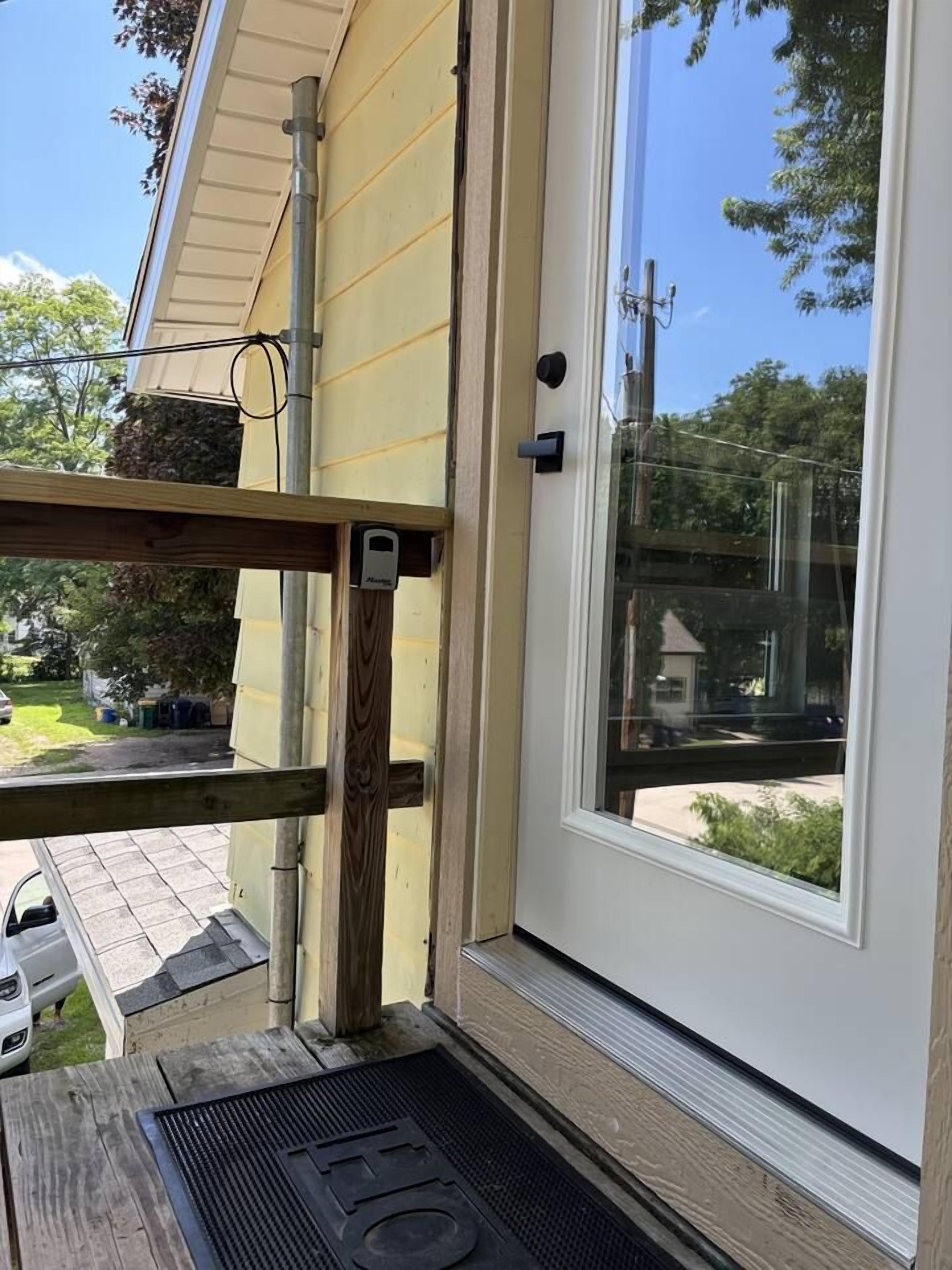 A door with a window, a doormat, and a small shelf with a device.