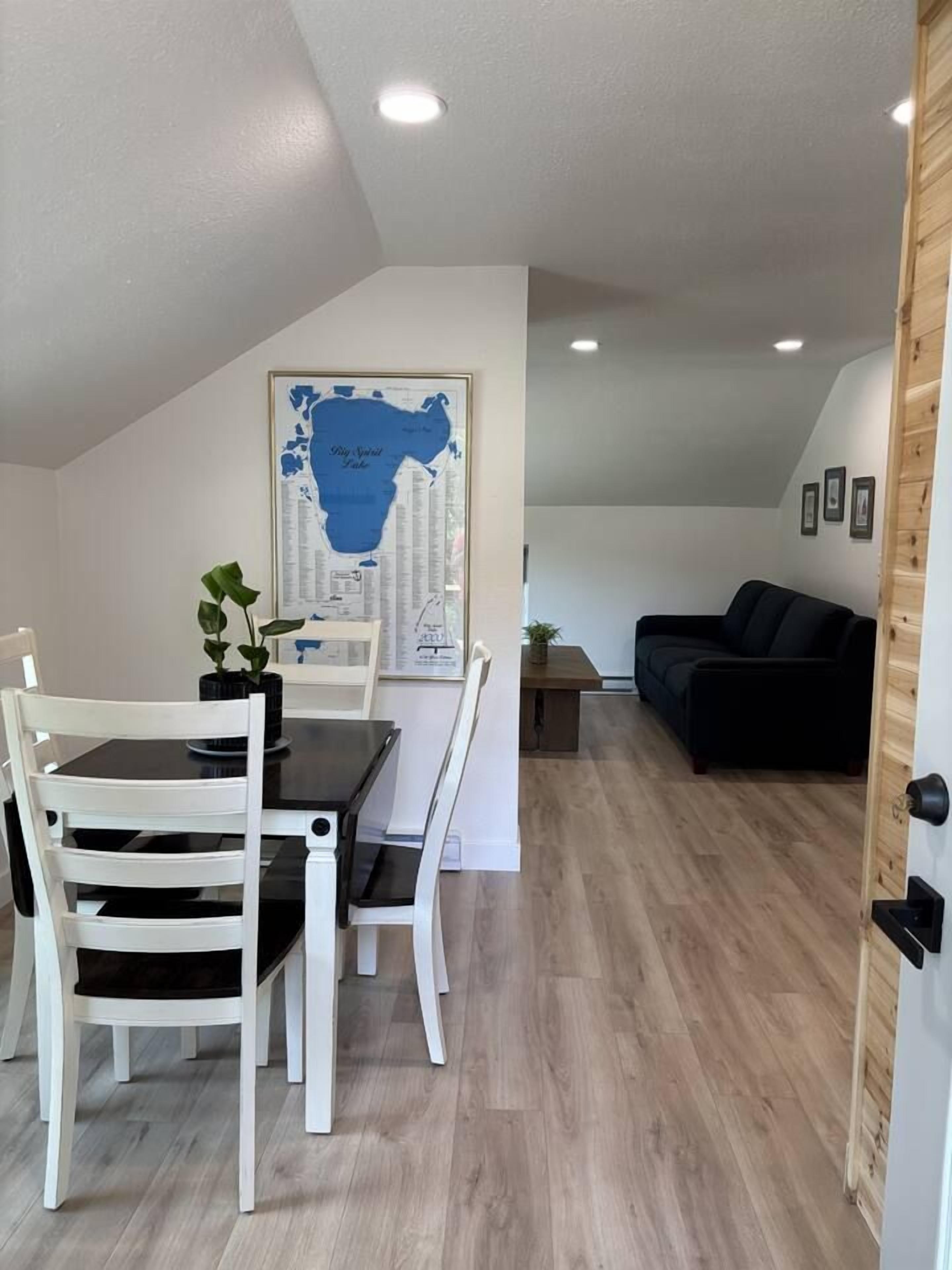 A dining area with a table and chairs, a map on the wall, and a living area with a couch.