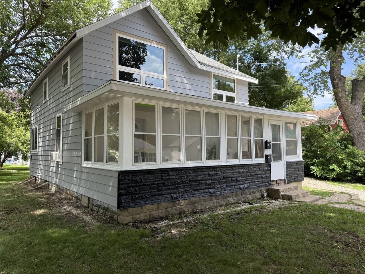 A two-story house with a covered porch and a stone foundation.