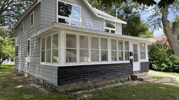 A two-story house with a covered porch and a stone foundation.