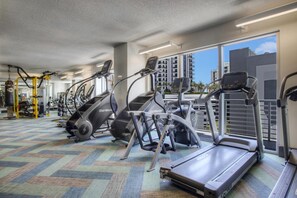 Une salle de sport équipée de tapis de course, de vélos d’exercice et d’appareils de musculation.
