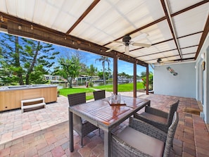 An outdoor patio with a covered seating area, a hot tub, and a view of a residential neighborhood. - Boater s Paradise Dock Hot Tub Cocoa Beach (Cocoa Beach)