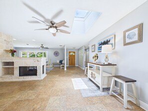 A spacious living area with a fireplace, a ceiling fan, and a view of the outdoors. - Boater s Paradise Dock Hot Tub Cocoa Beach (Cocoa Beach)