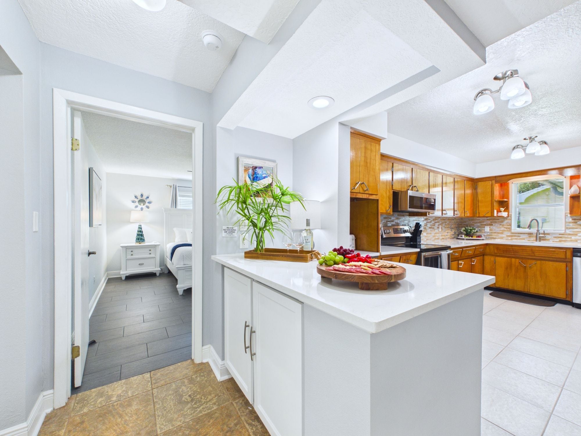 Una cocina moderna con muebles blancos, una isla central y un comedor con mesa y sillas blancas.