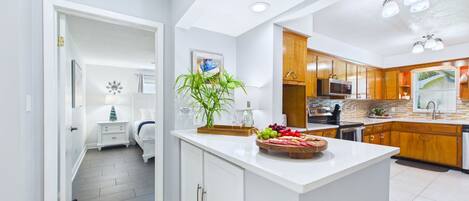 A modern kitchen with white cabinetry, a central island, and a dining area with a white table and chairs.