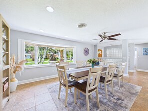 A dining area with a table, chairs, a ceiling fan, and a window with a view of greenery. - Boater s Paradise Dock Hot Tub Cocoa Beach (Cocoa Beach)