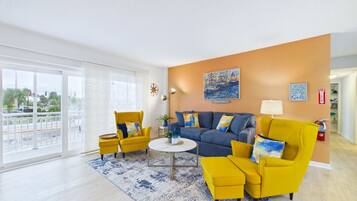 A modern living room with a sofa, armchairs, a coffee table, and a painting on the wall.