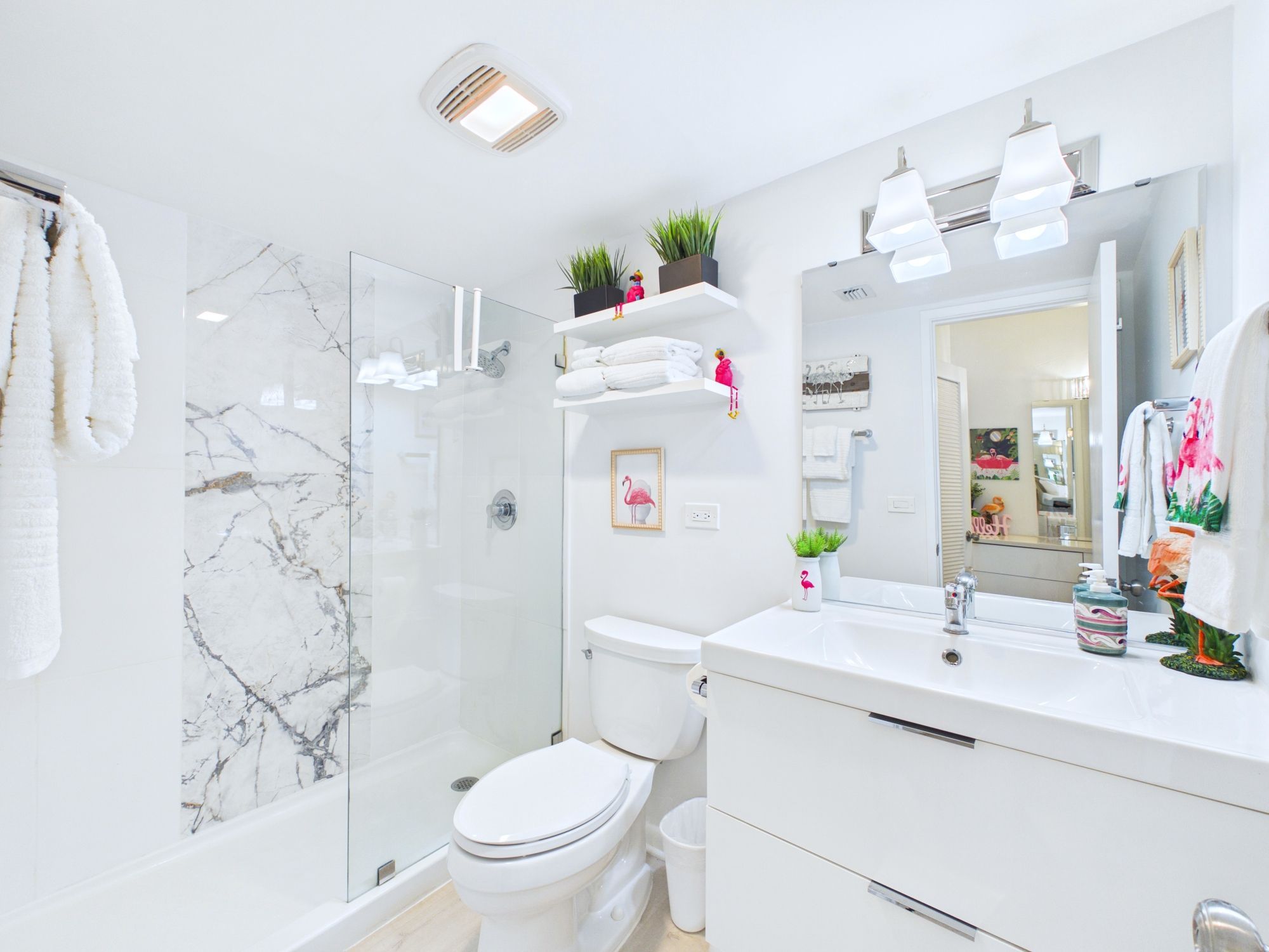 A modern bathroom with a glass shower enclosure, a white toilet, a vanity with a mirror, and a sink.