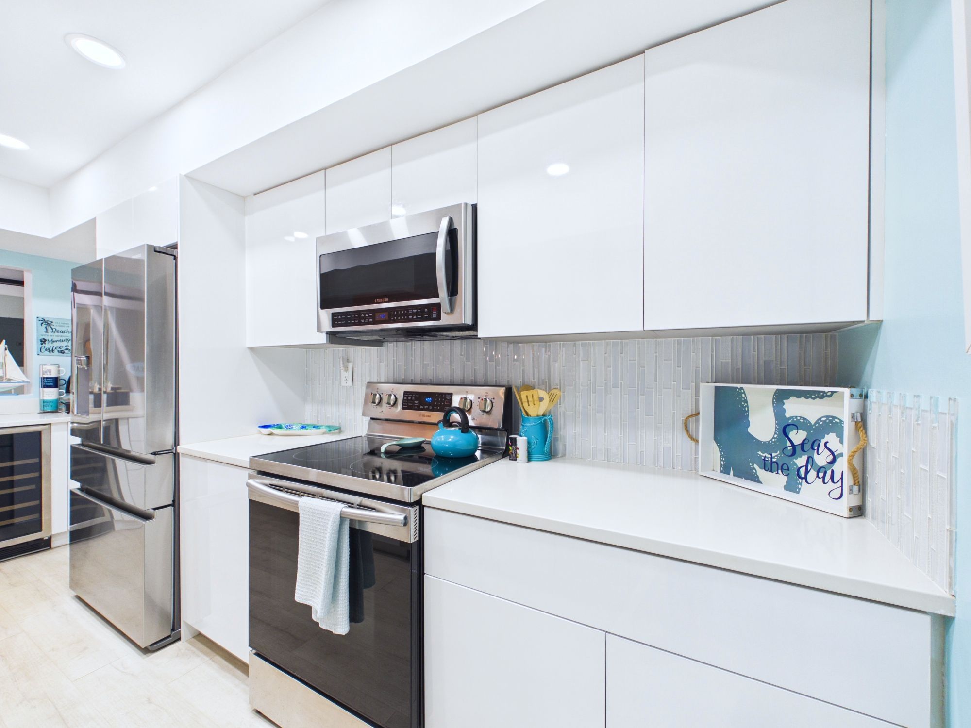 A modern kitchen with stainless steel appliances, a microwave, and a kettle on the stove.