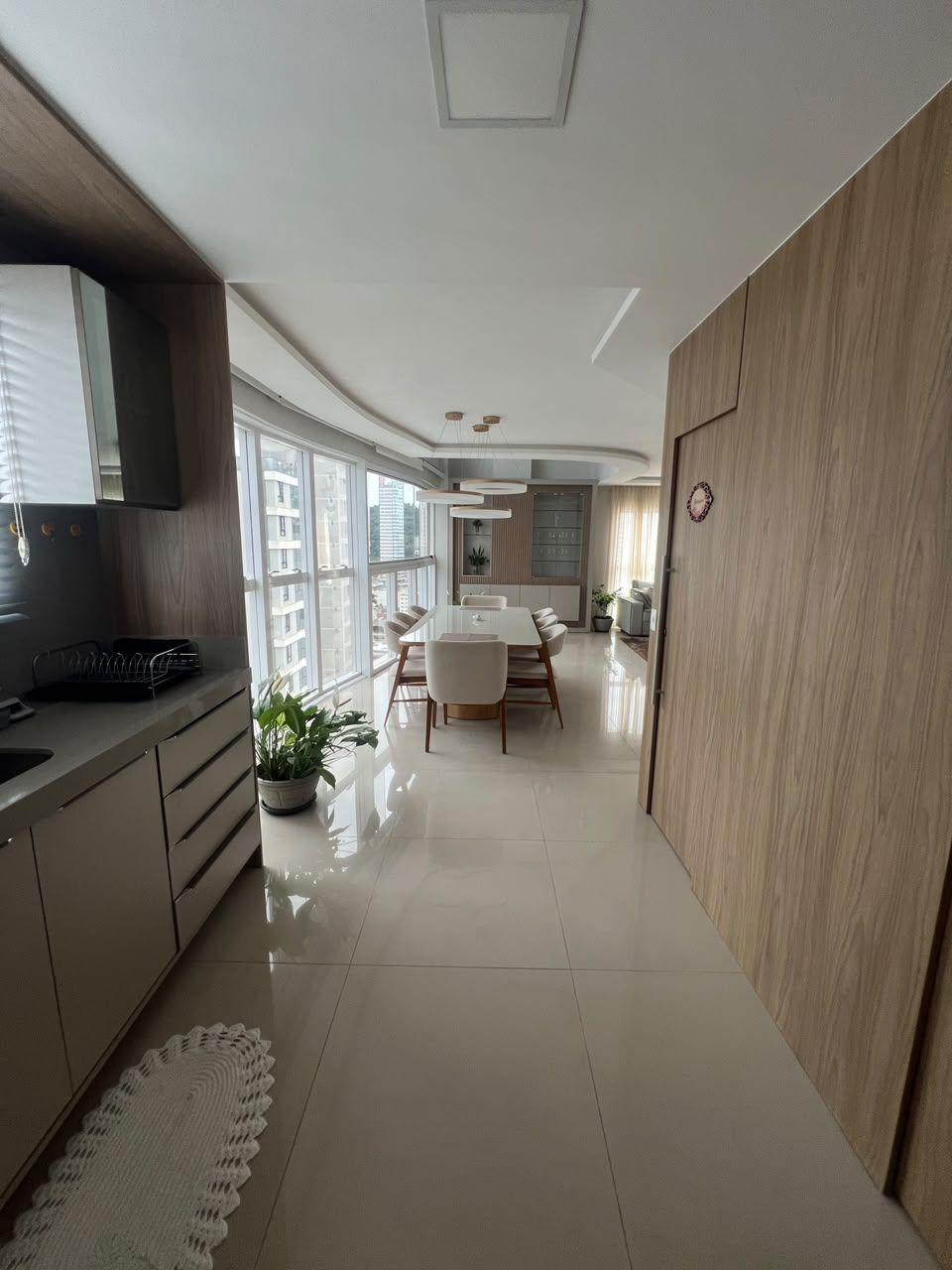 A modern kitchen with a dining area, large windows, and a view of the city.