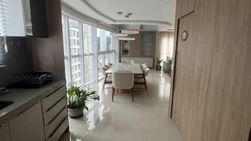A modern kitchen with a dining area, large windows, and a view of the city.