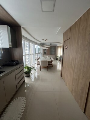 A modern kitchen with a dining area, large windows, and a view of the city.