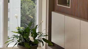 A room with a large window, a potted plant, and a mirror with vertical paneling.