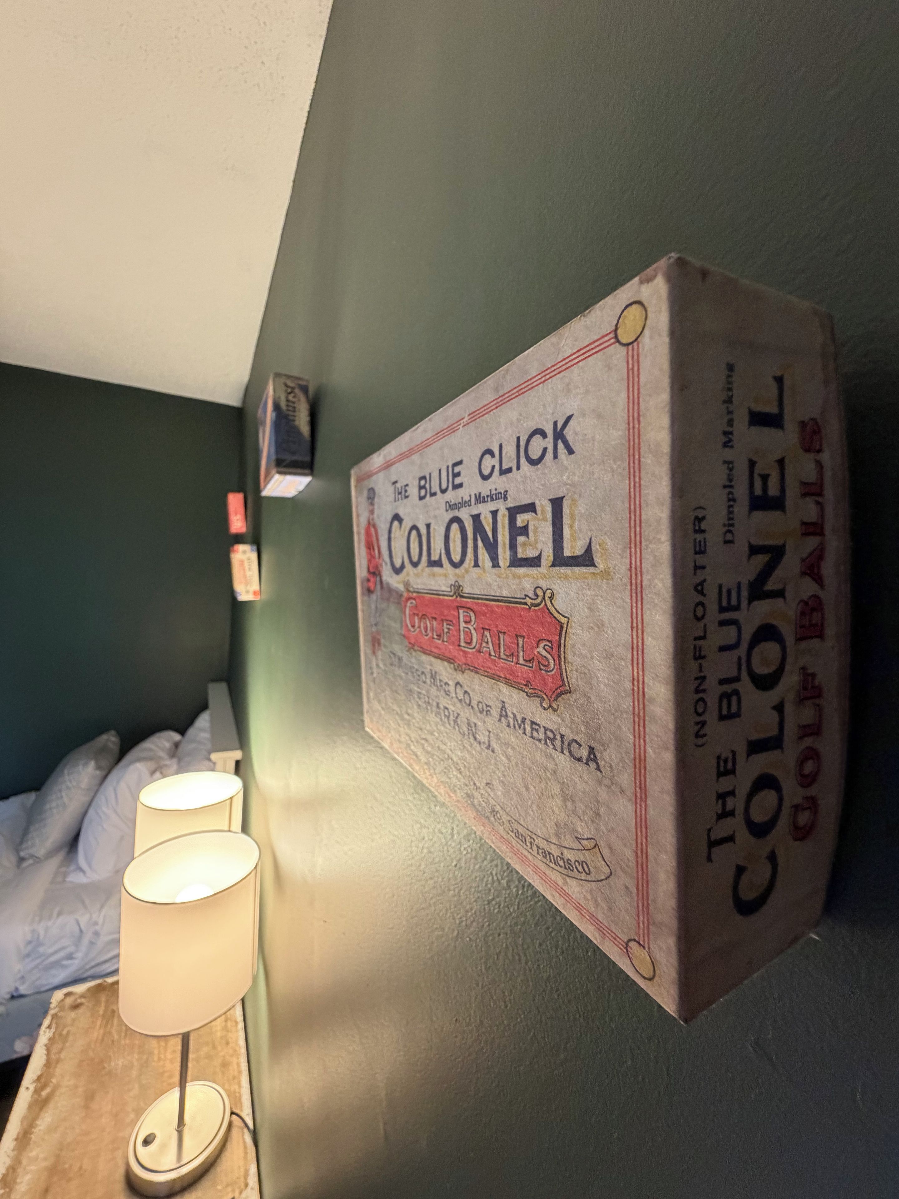 A wall-mounted box with text and a lamp on a bedside table.