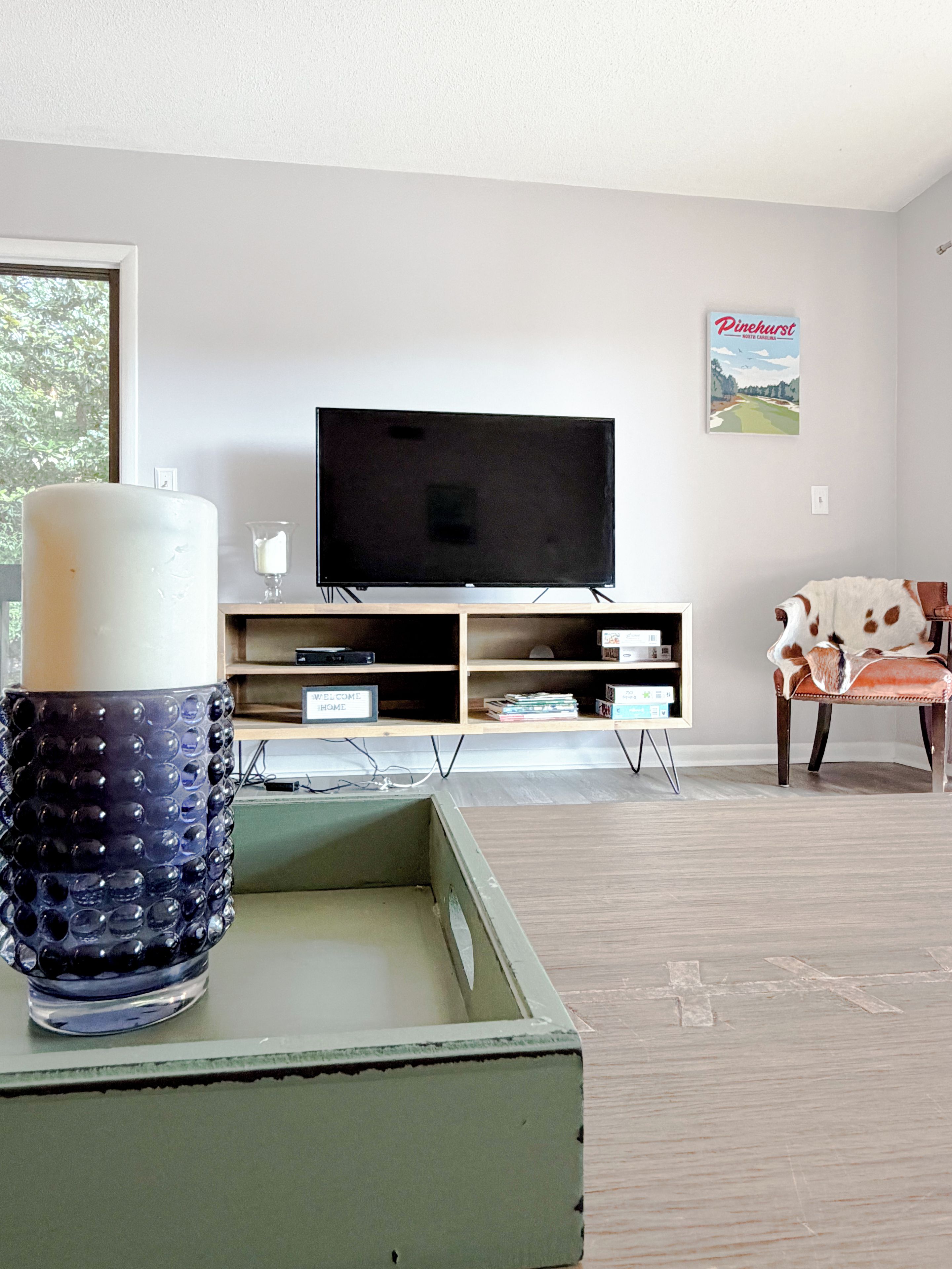 Una sala de estar con televisor, una vela decorativa y un cuadro en la pared.