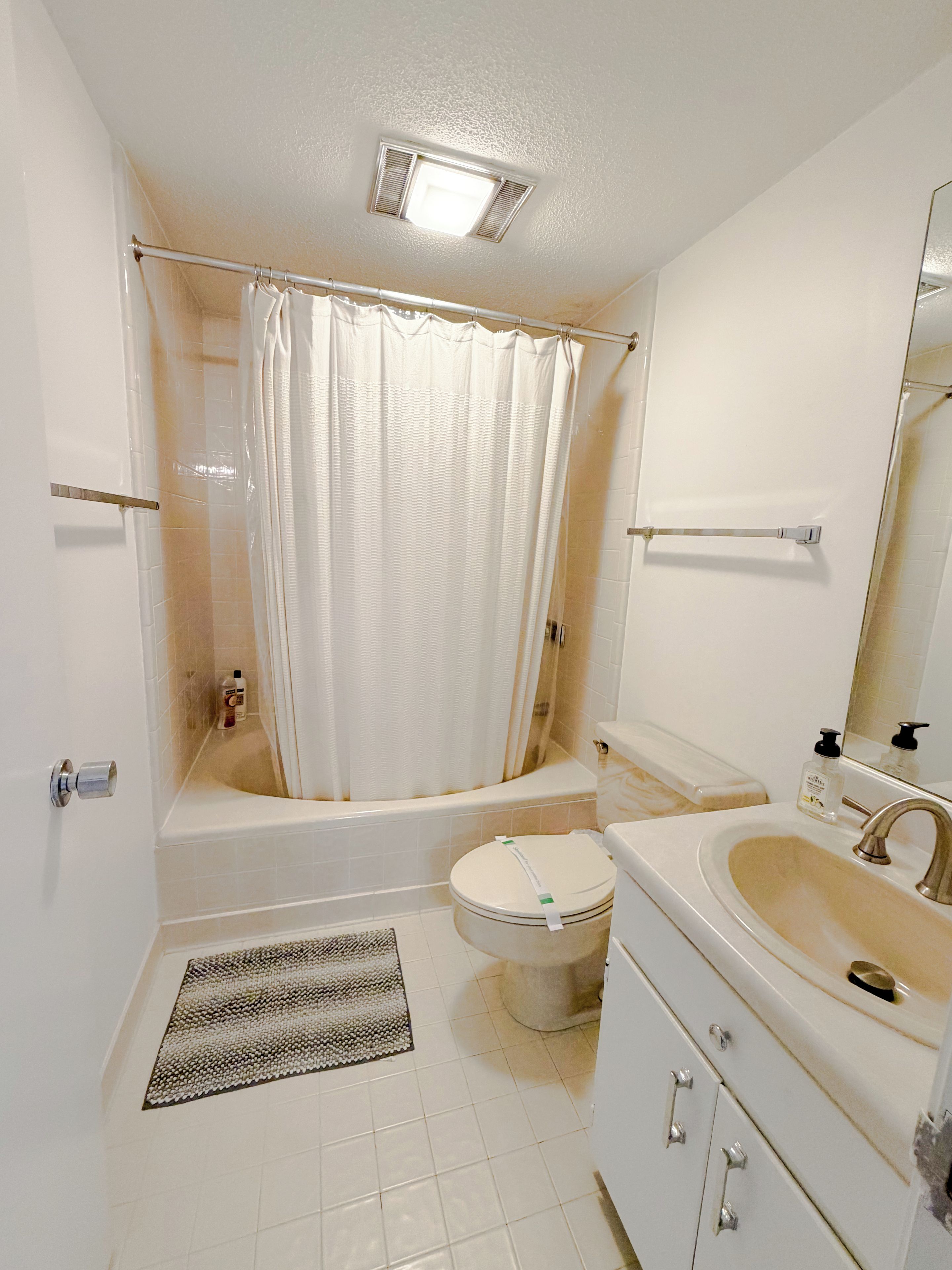 A bathroom with a bathtub, toilet, sink, and a shower curtain.