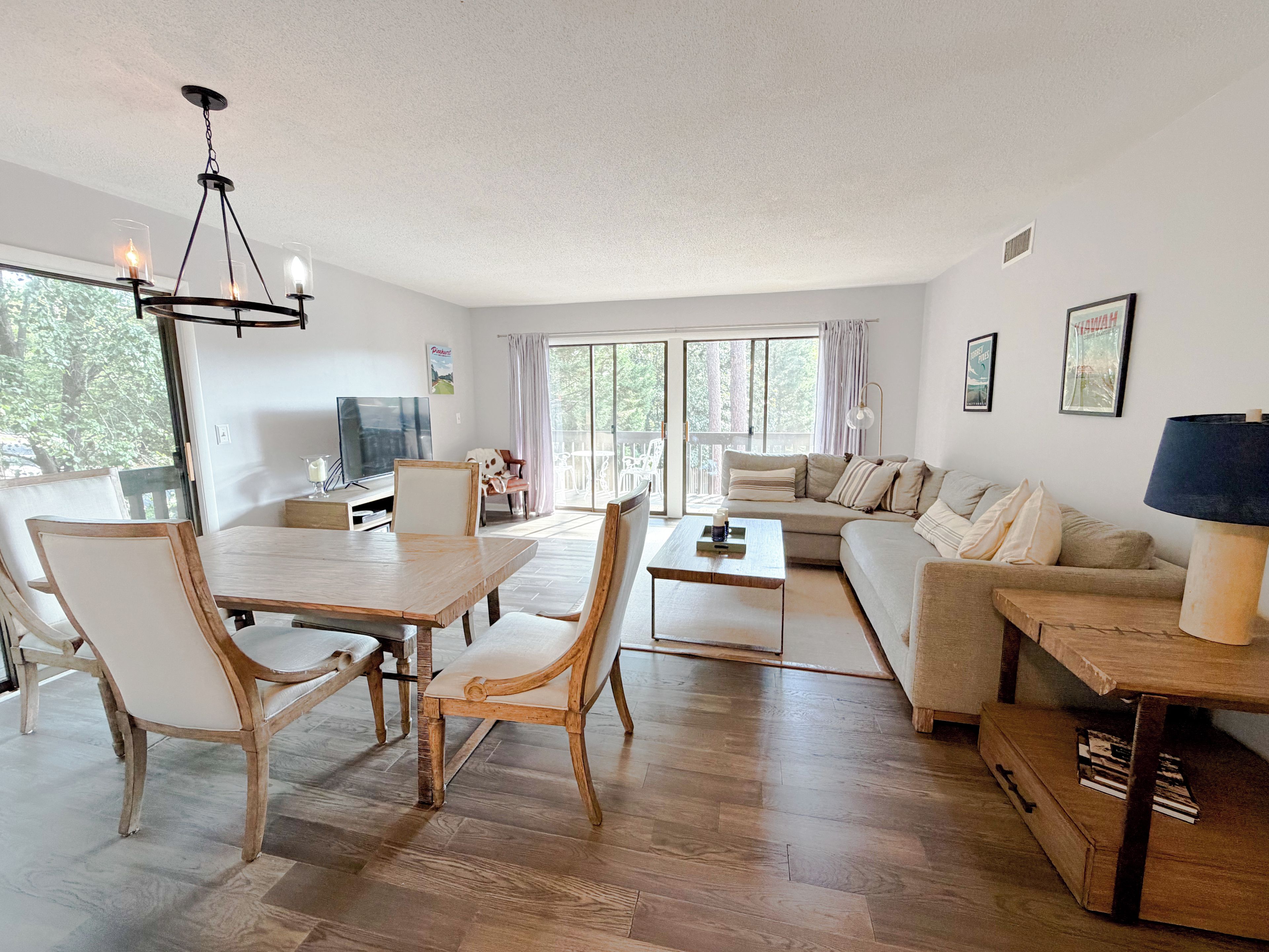 A modern living room with a dining area, a sofa set, and a television.