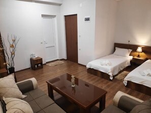 Et hotelværelse med to senge, en sofa, et sofabord og et lille natbord.
