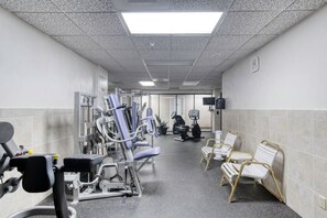 Ein Fitnessraum mit Trainingsgeräten, einem Fernseher und Sitzbereichen.