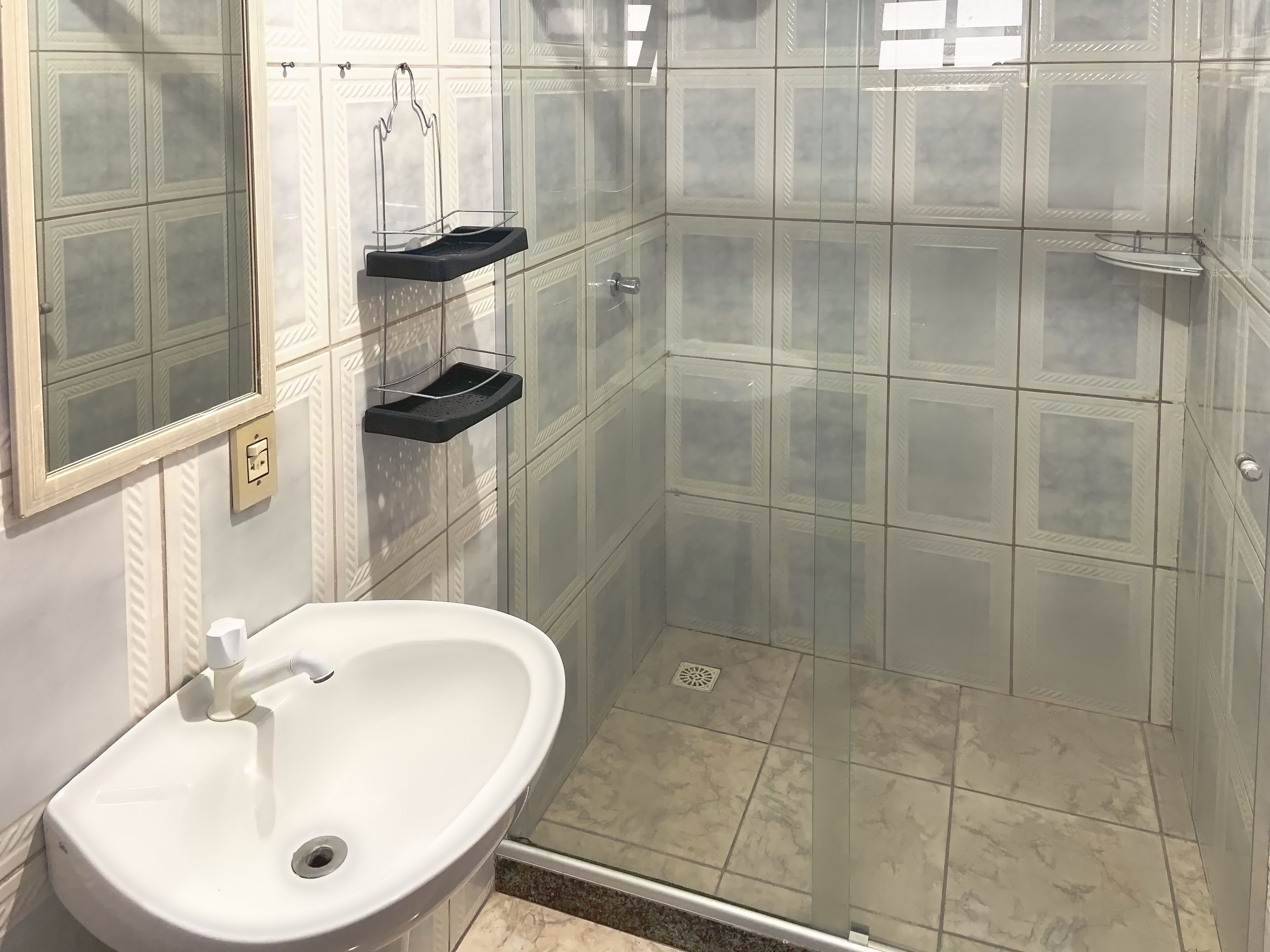 A bathroom with a white sink, a glass shower enclosure, and a mirror.