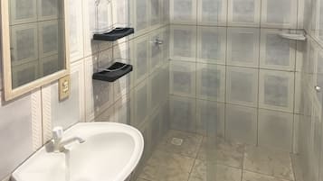 A bathroom with a white sink, a glass shower enclosure, and a mirror.