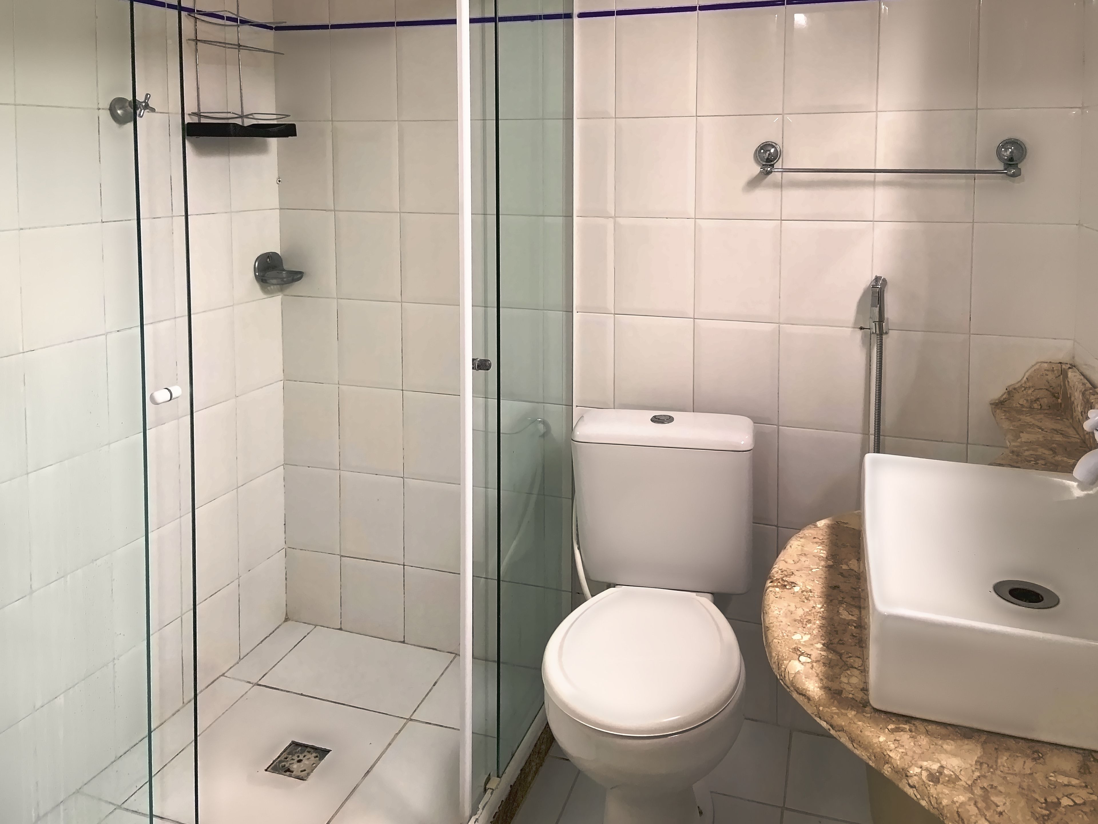 Un baño con ducha acristalada, inodoro y lavamanos con encimera de granito.