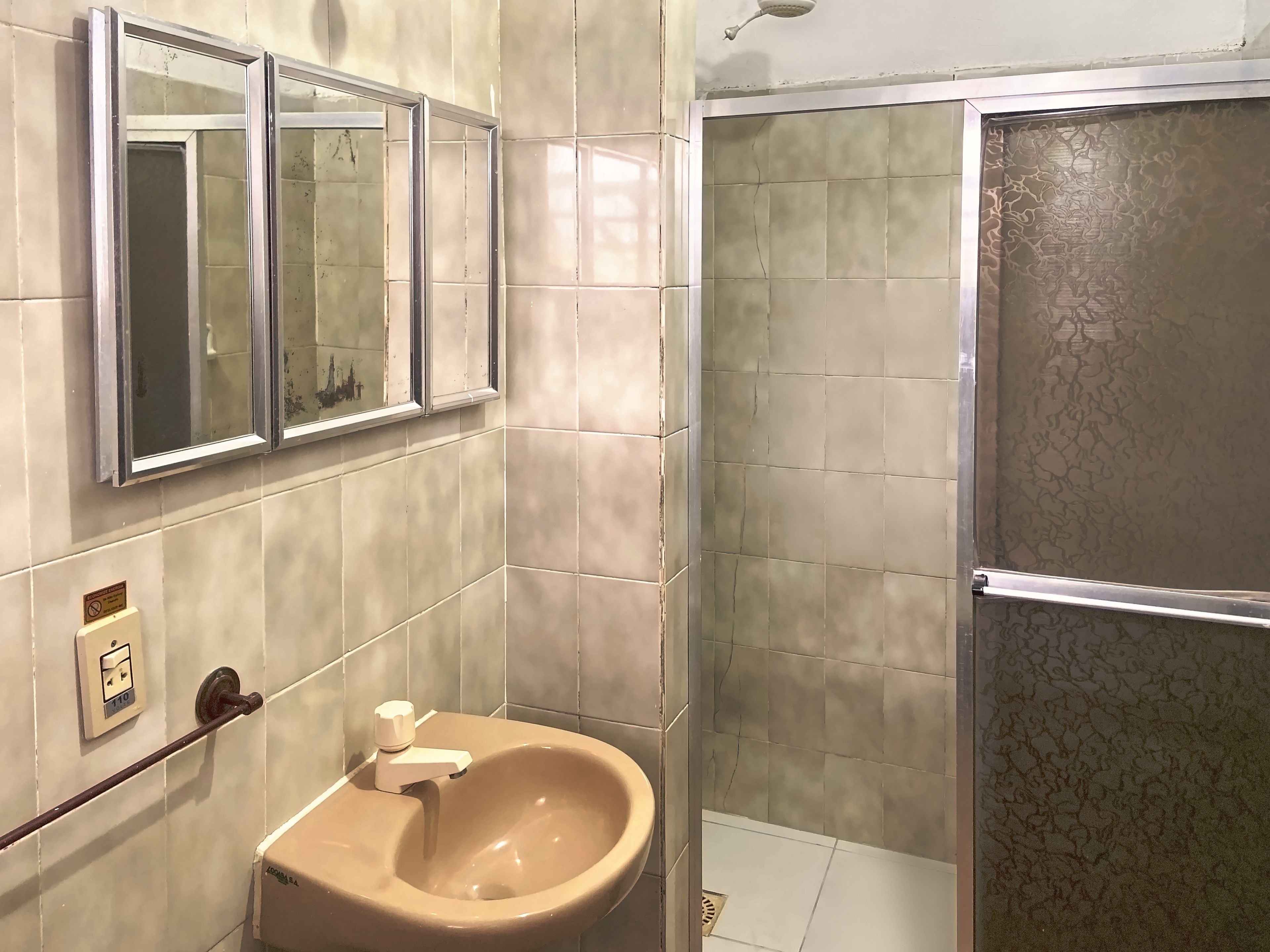 A bathroom with a beige sink, a mirror, and a shower enclosure.