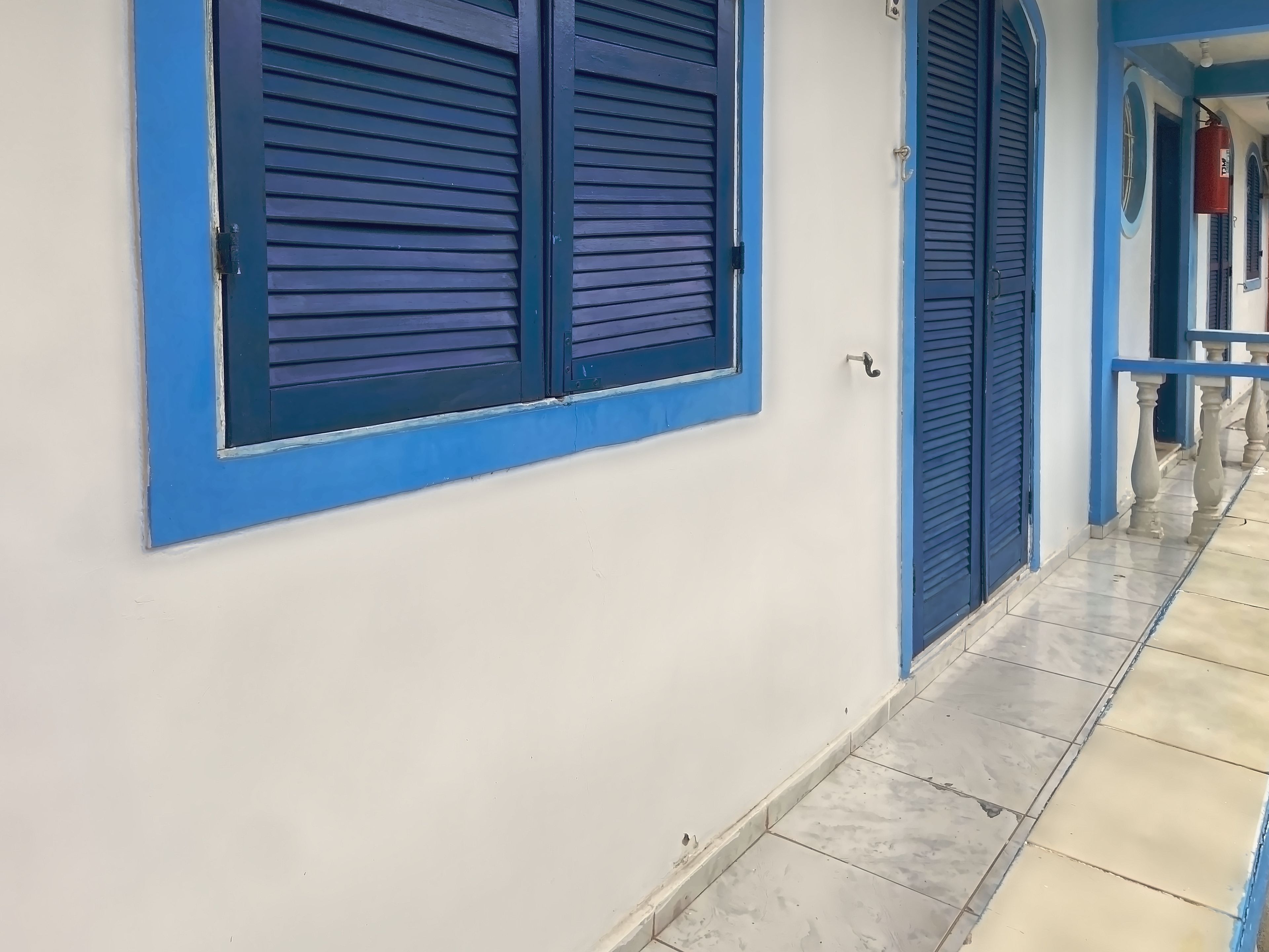 A corridor with a tiled floor and blue-framed windows.