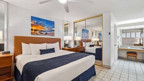 Una habitación de hotel con una cama grande, un escritorio, un espejo y obras de arte en las paredes.