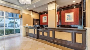 A hotel reception desk with a modern design, a large window, and a view of the outside.