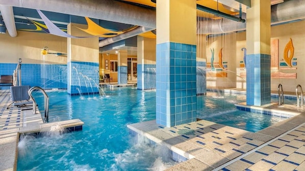 An indoor swimming pool with multiple water features, tiled walls, and a clear view of the pool area.