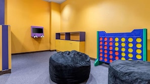 A room with a play area, including a bean bag chair, a small TV, and a colorful play structure.