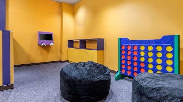A room with a play area, including a bean bag chair, a small TV, and a colorful play structure.