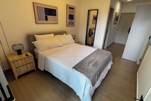 Een hotelkamer met een bed, nachtkastje en een spiegel.