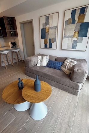 A modern living room with a sofa, two round tables, and abstract art on the wall. - Modern 1BR with Balcony and Sofa Bed -4 guests (Panamá)