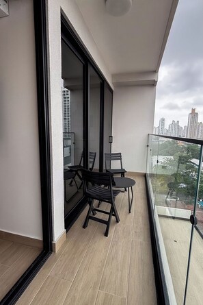 A balcony with a glass railing, a table, and two chairs. - Modern 1BR with Balcony and Sofa Bed -4 guests (Panamá)