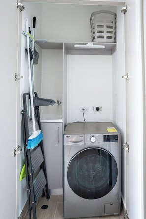 A compact laundry room with a washing machine, a broom, and a laundry basket. - 2 bedrooms/2 bathrooms at The Hub, San Francisco PTY (Panamá)