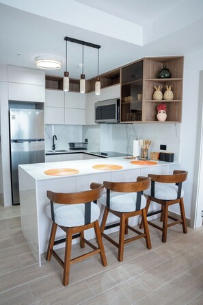 A modern kitchen with a central island, wooden chairs, and built-in appliances. - 2 bedrooms/2 bathrooms at The Hub, San Francisco PTY (Panamá)