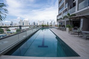 A rooftop swimming pool with a city skyline view, lounge chairs, and potted plants. - Vrbo Property (Panamá)