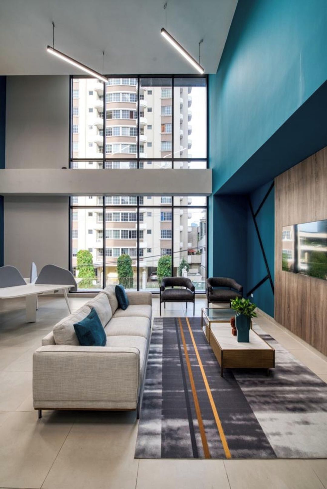 Ein modernes Interieur mit einer Couch, Sesseln, einem Couchtisch und Blick auf ein Gebäude durch große Fenster.