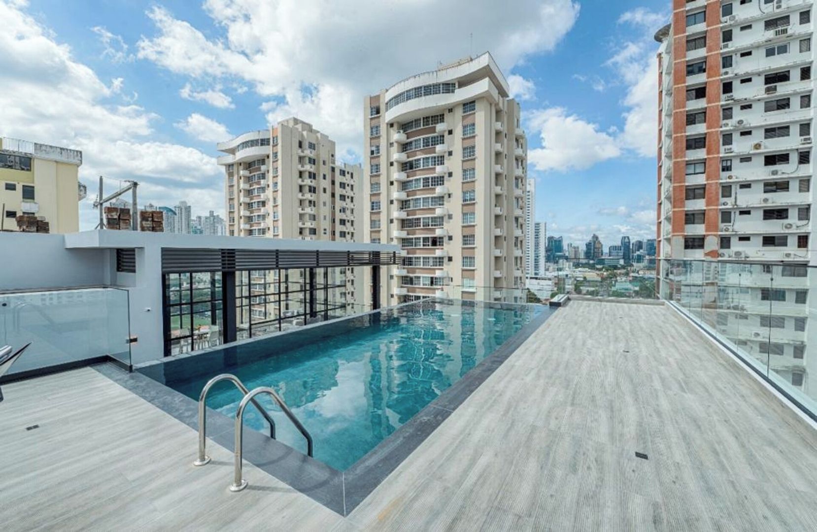 Ein Pool auf dem Dach mit Blick auf die Stadt, umgeben von Hochhäusern.