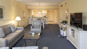 A living room with a sofa, armchair, coffee table, and a television on a cabinet. - Waterside by Spinnaker - 2BR Hilton Head Condo, Short Walk to the Beach (Hilton Head Island)