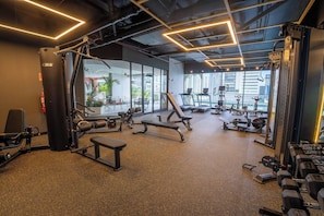 A gym with various exercise equipment, large windows, and a view of buildings. - Hotel-Style Room at The Hub, San Francisco (Panamá)