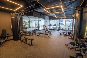 A gym with various exercise equipment, large windows, and a view of buildings. - Modern 1-Bedroom Apartment in The Hub / Pool / Gym / Upper Floor (Panamá)