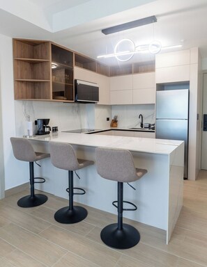 A modern kitchen with a central island, bar stools, and built-in appliances. - Modern 1-Bedroom Apartment in The Hub / Pool / Gym / Upper Floor (Panamá)