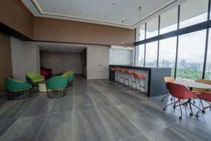 A modern interior with a bar area, seating, and large windows offering a city view. - Hotel Room at The Hub, San Francisco (Panamá)