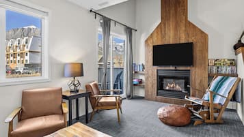 Un salon moderne doté d’une cheminée, de sièges confortables, d’un téléviseur et offrant une vue sur les montagnes.