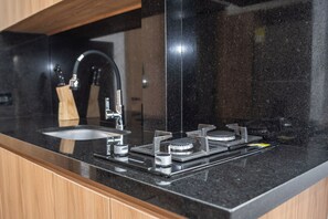 Een keuken met een zwart aanrecht, een roestvrijstalen spoelbak en een gasfornuis.