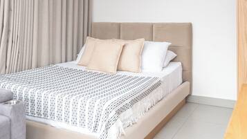 Una camera da letto moderna con un letto grande, una poltrona grigia e un comodino in legno.
